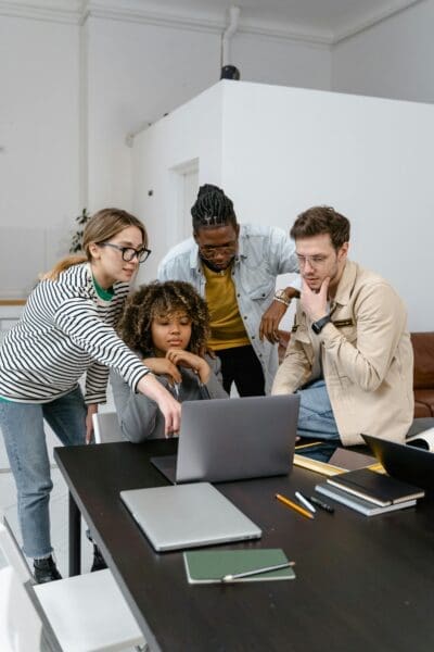 Employees working on laptops in a modern office, reflecting the impact of technology driven culture on workplace communication and collaboration